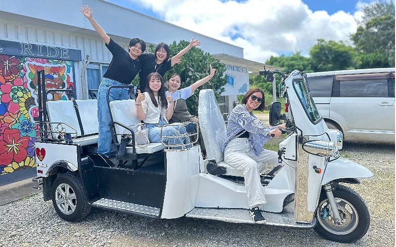 五位女性乘坐一輛白色三輪車