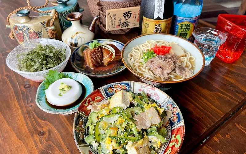 沖繩傳統料理套餐，包含海葡萄、苦瓜炒豆腐、沖繩麵與滷豬肉，搭配當地美酒的美食體驗