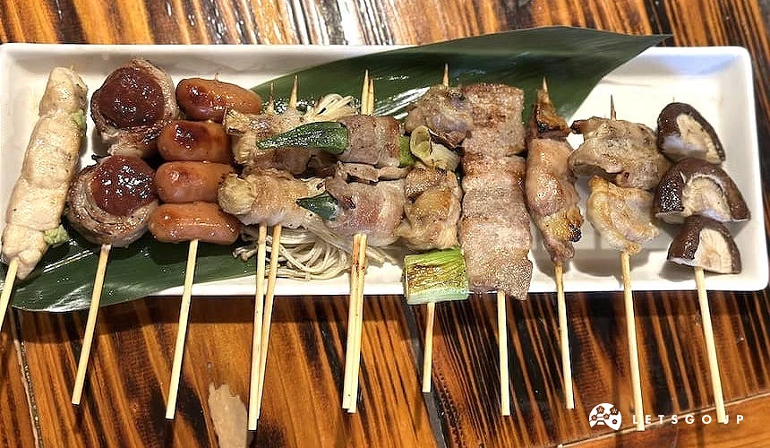 「串角」的串燒擺在白色的盤子上,有雞肉串、小香腸、肉卷、香菇等等