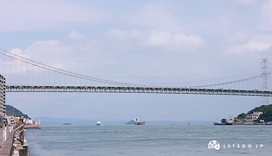跨海大橋橫跨水面,下方有貨船與小船航行