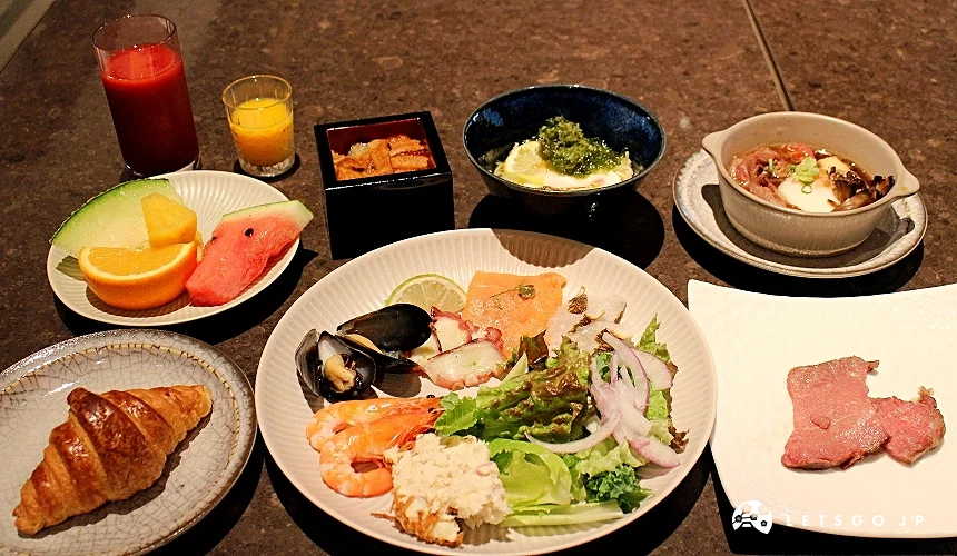 擺放生魚片沙拉、水果、麵包與飲品的餐點