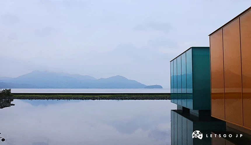 湖畔倒映彩色方形建築,遠方可見山景