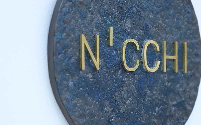 深藍色圓形石板上以金色字體寫著「N’CCHI」