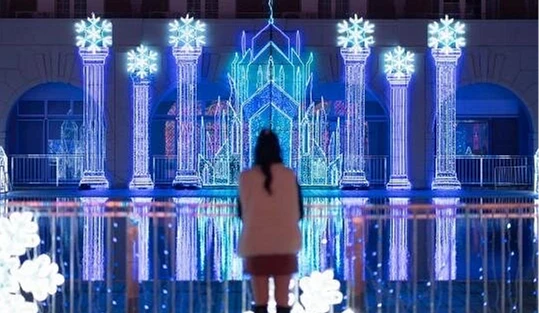 以藍白燈光打造的冰之宮殿主題裝置,倒映在水面上宛如童話世界