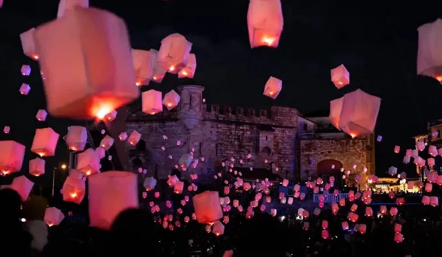 夜晚活動現場升起無數粉紅色天燈,映照出古城牆與人群剪影,場面夢幻又壯觀