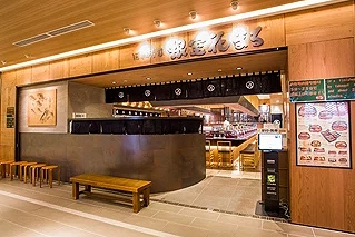 札幌车站 STELLAR PLACE 内的回转寿司名店「根室花丸」店面外观,温润木质设计与开放式吧台座位营造温馨氛围