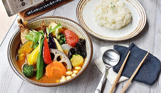 札幌车站 APIA 地下商场的汤咖哩名店 Rojiura Curry SAMURAI,碗中盛满色彩缤纷的蔬菜与鸡腿肉,搭配一盘白饭