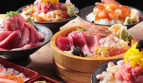 多款色彩繽紛的海鮮丼整齊擺放在木桌上,包括鮪魚丼、蟹肉海膽丼、鮭魚卵甜蝦丼等,鮮紅魚肉與金黃蛋絲交織