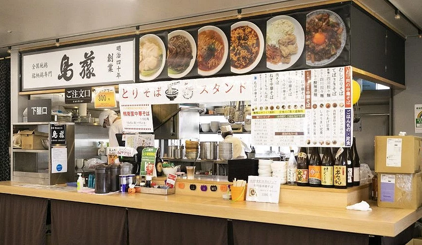 「鳥飯 鳥藤分店」店內櫃台,全木質吧台設計乾淨明亮,牆上掛有多款親子丼與雞肉料理照片