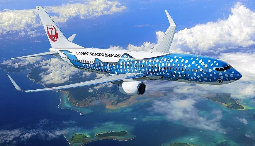 日本越洋航空(JTA)鯨鯊彩繪波音737-800客機在藍天與海洋上飛行,機身以藍白波點設計呈現鯨鯊圖案
