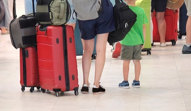 旅客推著紅色行李箱在機場排隊托運