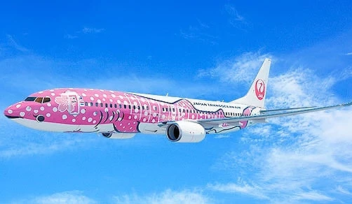 日本越洋航空(JTA)粉紅色鯨鯊彩繪波音737-800客機在藍天中飛行,機身以粉白波點描繪鯨鯊造型