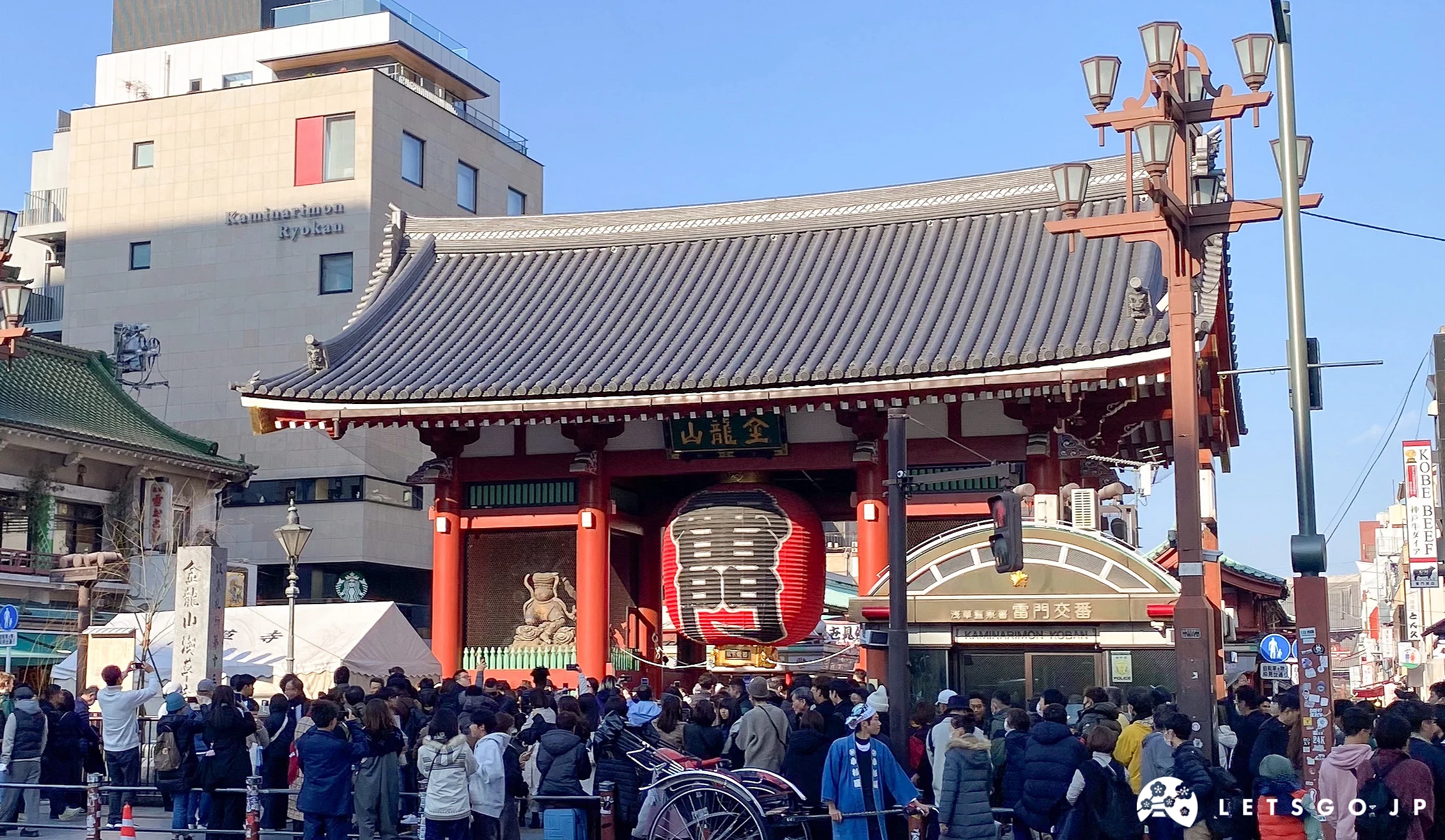 紅色的雷門燈籠懸掛著,有許多觀光客爭相與雷門合照。畫面中也有淺草最著名的人力車