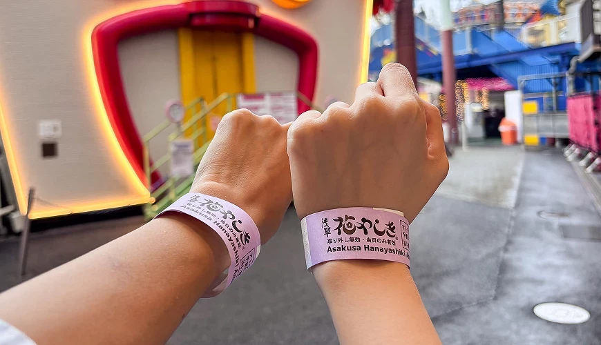 兩隻手的手腕上套有一日通票的手環