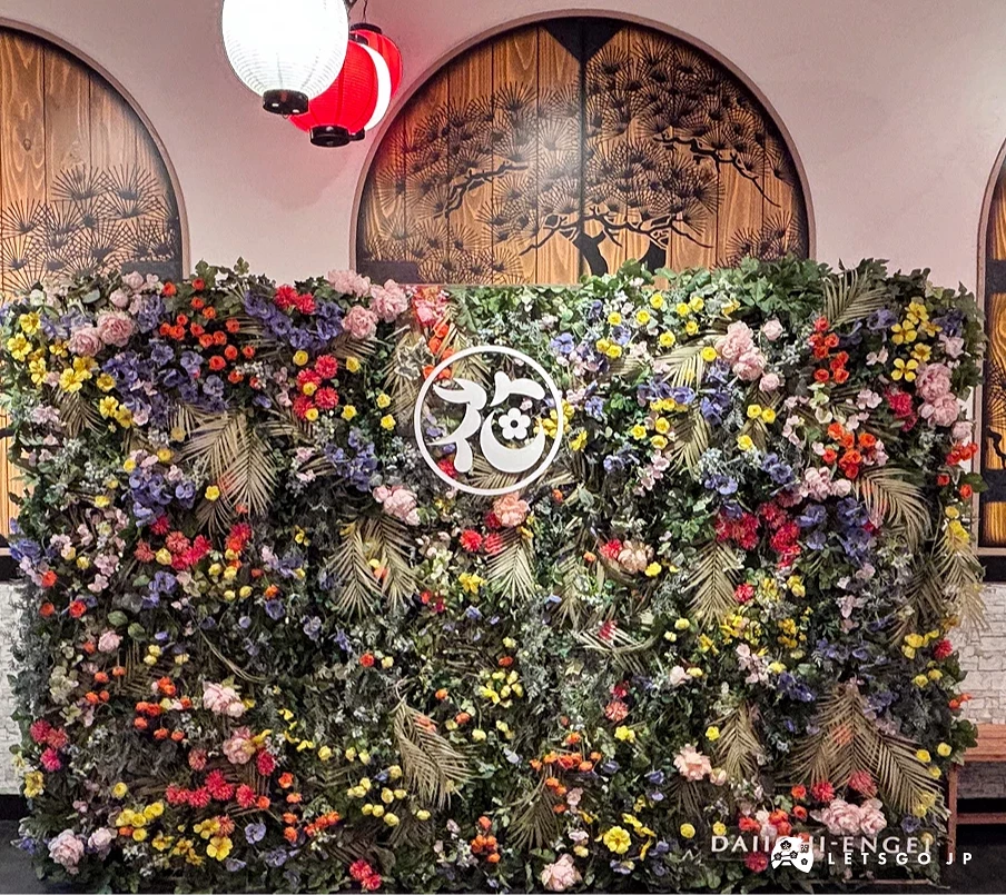 設計美觀的拍照牆,由花與綠植所組成,上面則有日式祭典的紅白燈龍裝是