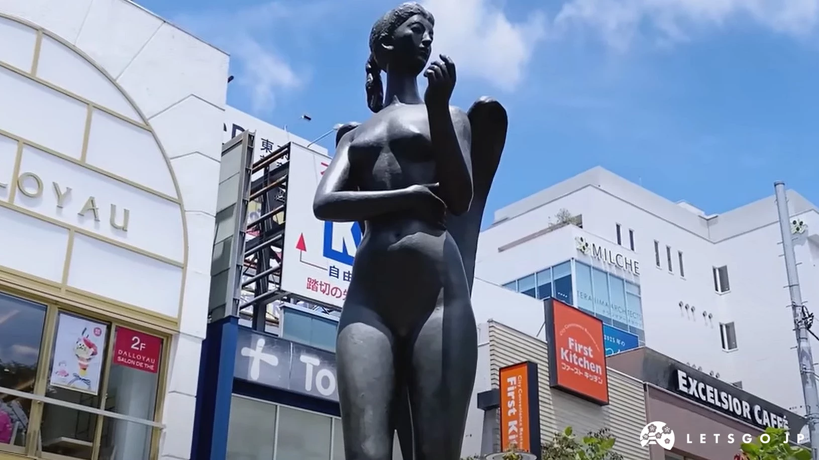 户外的黑色女性雕像,背景为蓝天和建筑物。