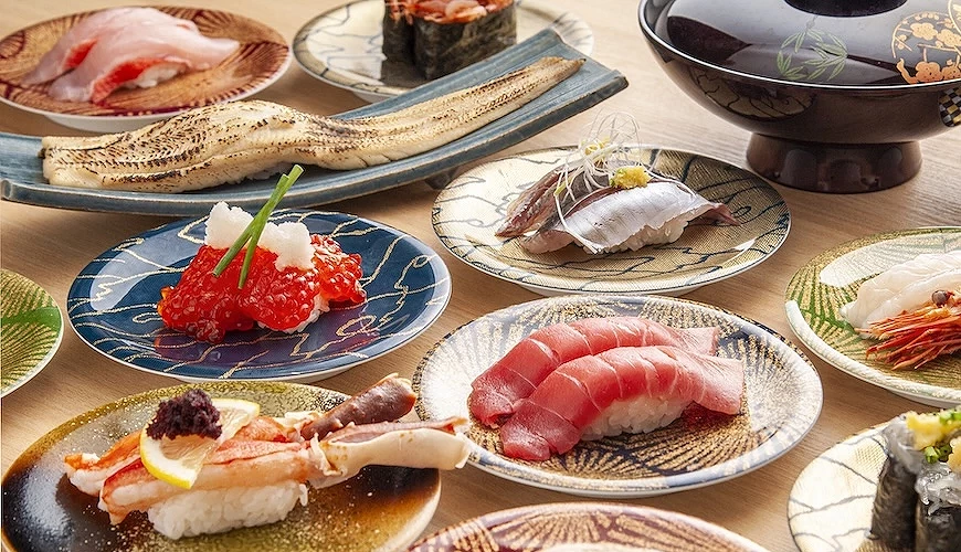 桌上排满装了各种料寿司的圆形盘子