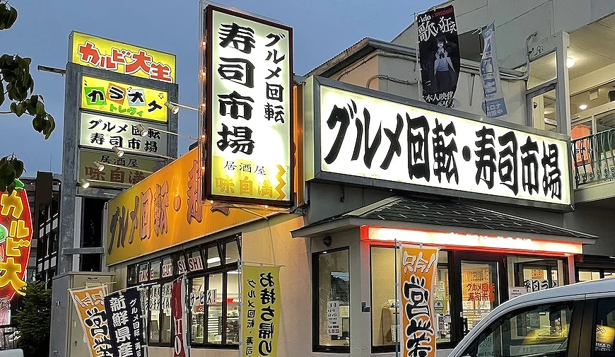 回转寿司市场店面白底黑色书法字的招牌,店门口版放众多旗帜