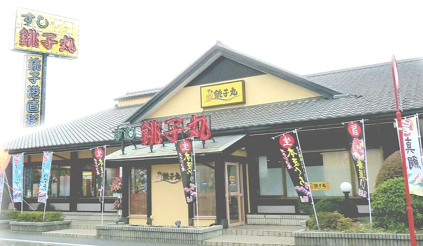 铫子丸本店是一间独栋建筑,日式屋瓦搭配黄色招牌,及红色大字的霓虹灯logo