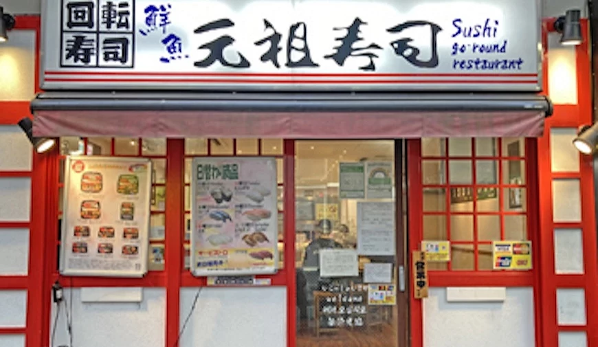 元祖寿司的店面用红色木框与白色墙壁,白色大大的招牌写着黑色书法字