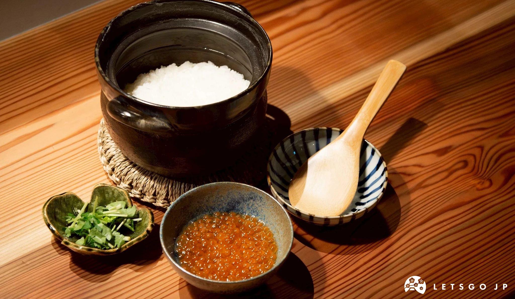 一碗盛滿白飯的日式陶鍋或飯碗,旁佐以一小碗鮭魚卵