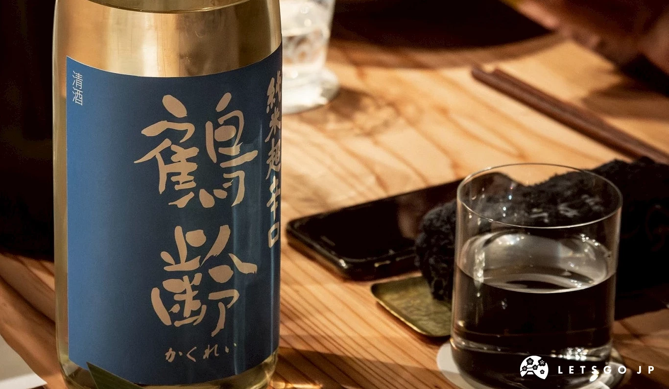 一瓶清酒或燒酒瓶身特寫,旁有小碟小菜和正在用餐的客人