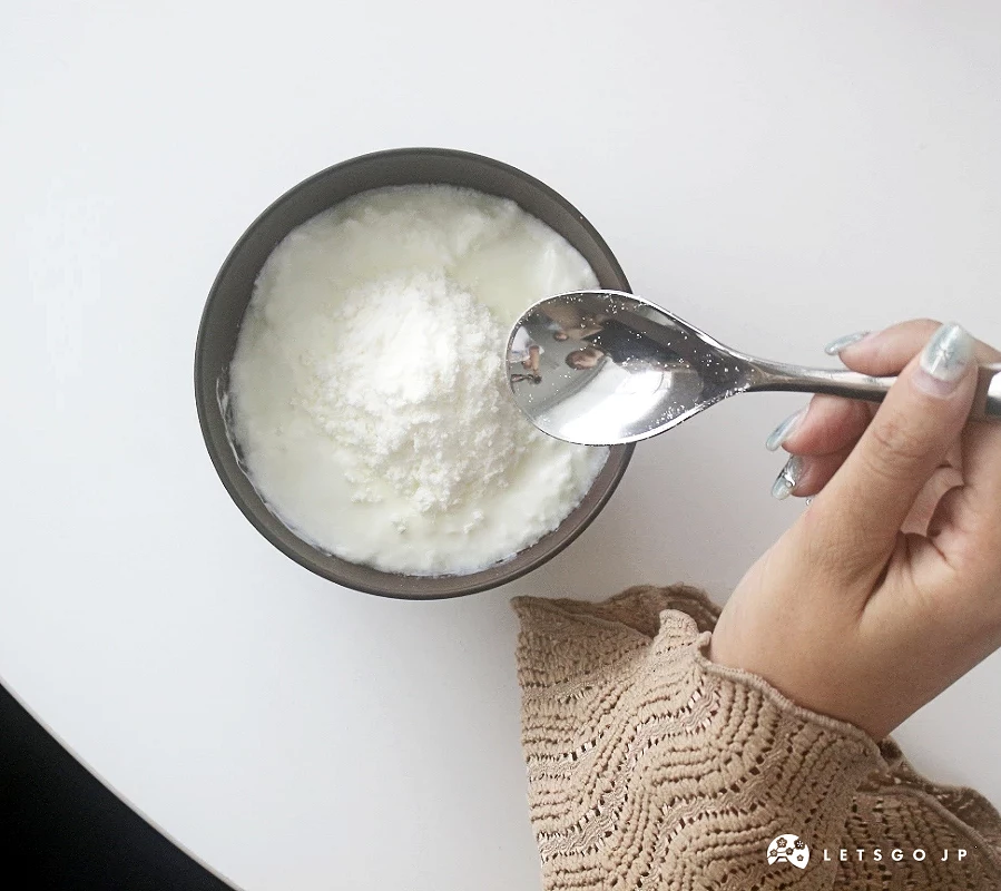 一湯匙優格被舀起,優格已混合膠原蛋白粉。