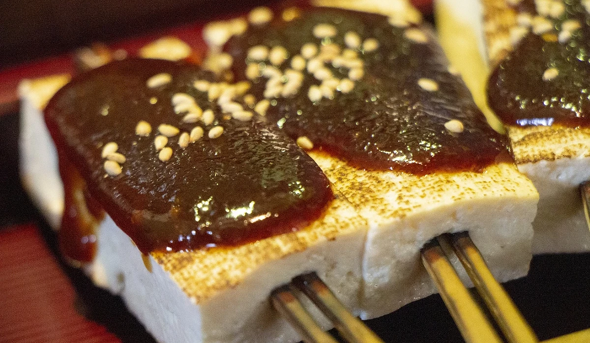 兩塊方形烤豆腐,上面鋪著深棕色的濃稠醬料和淺色的花生粒或芝麻。