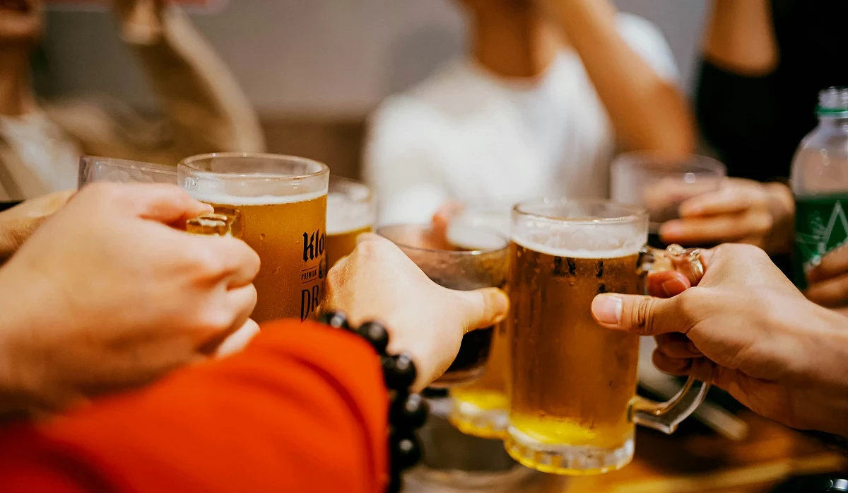 特寫鏡頭下,幾位朋友正在居酒屋裡互相舉杯碰杯,準備暢飲啤酒。