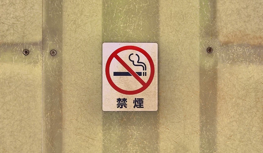一個貼在牆上的圓形白色標誌,圖案為香菸被紅線劃過,表示禁止吸菸。