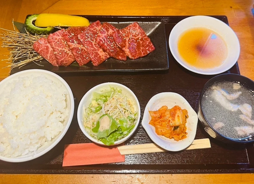 白飯與生菜與湯品與肉片的定食放在盤子上