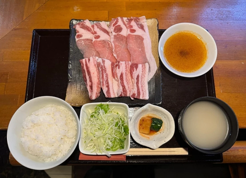 白飯與生菜與湯品與肉片的定食放在盤子上