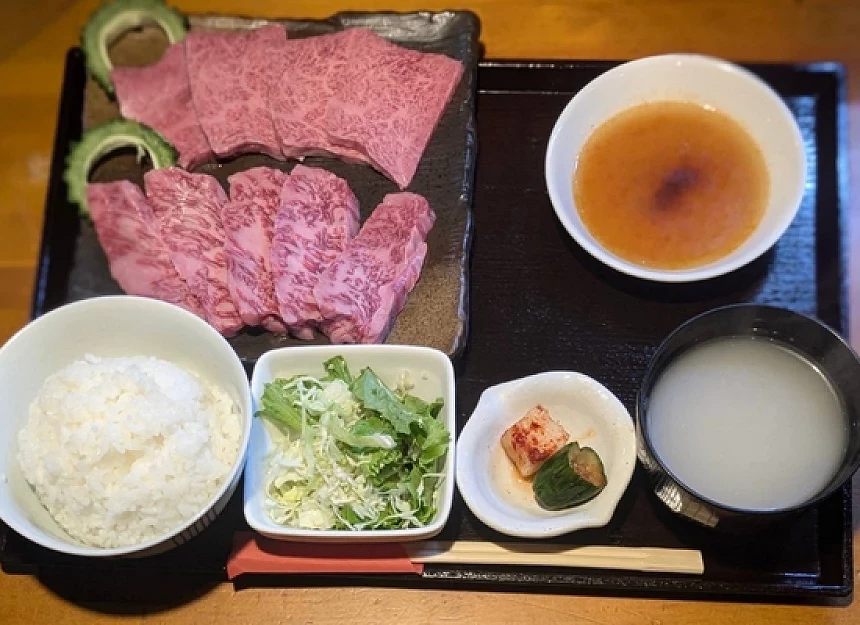 白飯與生菜與湯品與肉片的定食放在盤子上