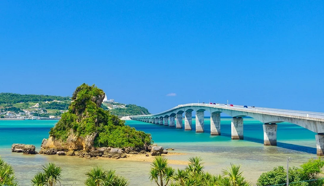 冲绳古宇利大桥横跨碧蓝海面,连接屋我地岛与古宇利岛,远眺湛蓝天空与清澈海水交织出美丽景色