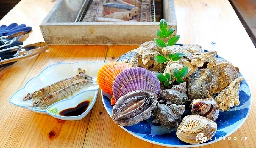 一盤豐盛的海鮮與蝦子,旁邊擺有醬汁與燒烤用具