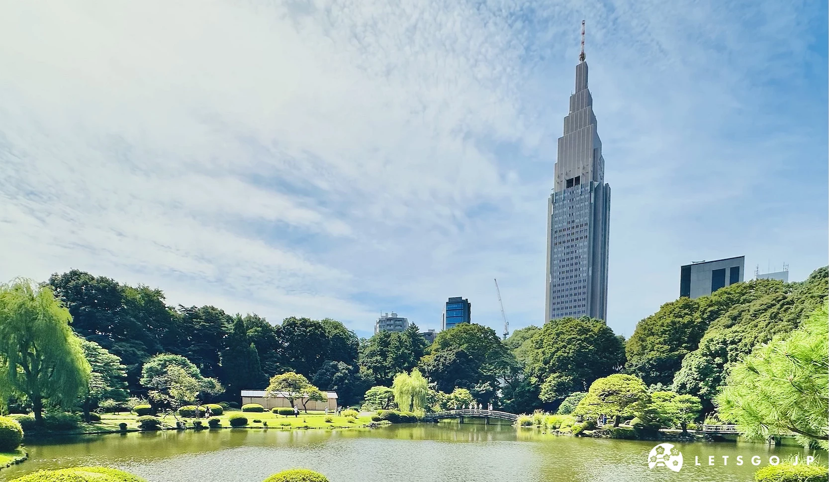 新宿御苑內的上之池,遠處有一整排的樹木,最後有一棟高聳的高樓