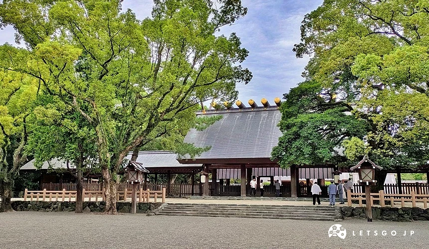 熱田神宮本宮建築坐落於綠樹之間,前方石地寬敞,少數參拜者在社殿前行禮