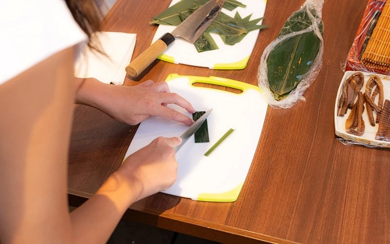 女子在砧板上切割綠色竹葉