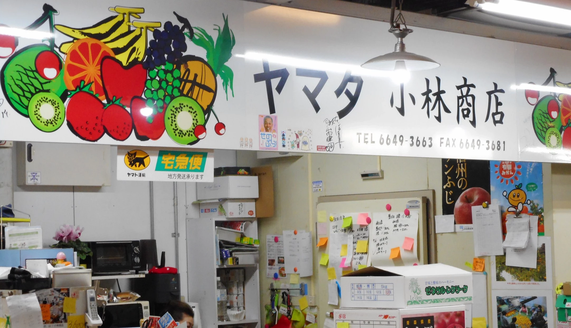 小林商店的蔬果招牌,白色招牌上面画满了各式水果的图样