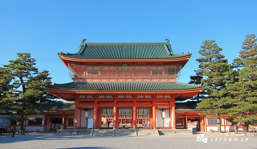 平安神宮的應天門,朱紅色大門搭配綠色屋瓦,前方為寬敞石地,兩側可見成排松樹