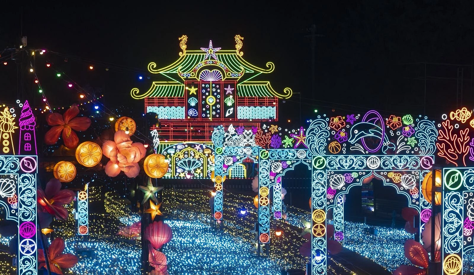 夜空下的龙宫城主题灯饰闪耀缤纷光芒,霓虹线条勾勒出海洋生物与华丽宫殿轮廓