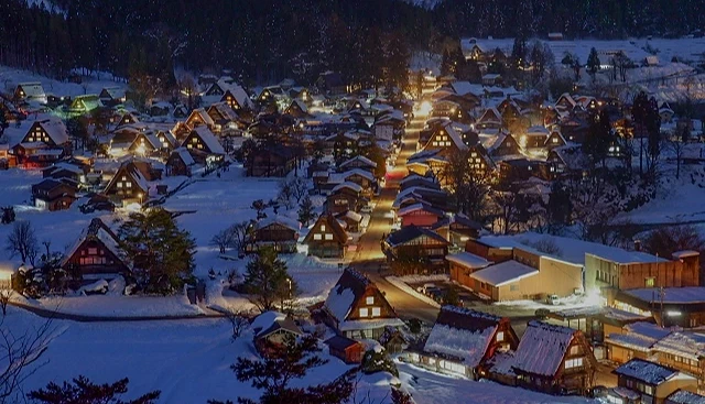 冬夜的白川乡合掌造村落在雪地中闪耀,屋顶覆雪、街道被灯光照亮