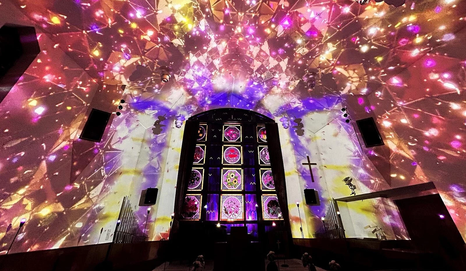 教堂内墙被绚烂投影映照,彩光在空间中绽放,如万花筒般梦幻