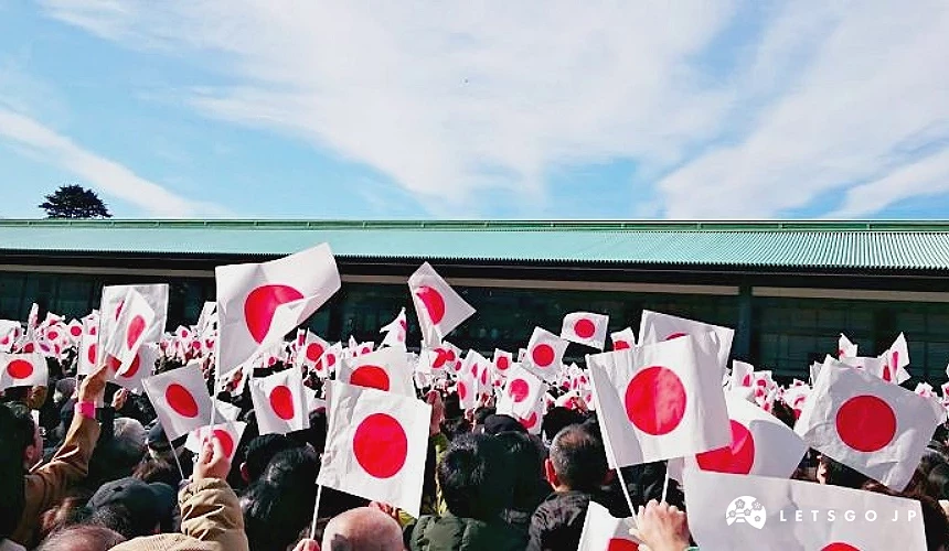 大量民众在皇居前挥舞日本国旗,排队参加元旦新年一般参贺活动,背景可见皇居建筑与蓝天