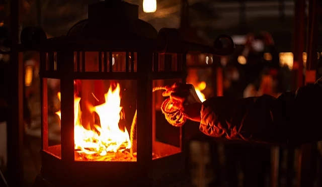 夜间的神社境内,民众将绳子靠近灯笼内的火焰点燃