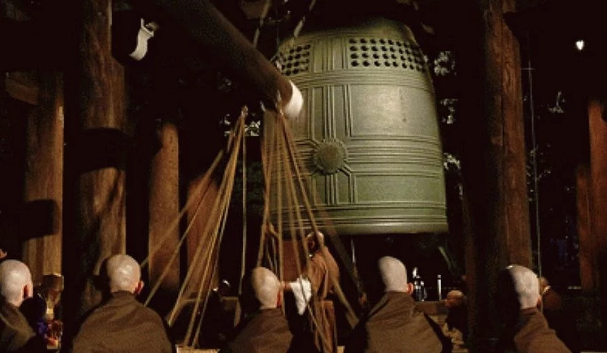 多名僧侣合力拉动粗绳敲击知恩院巨大的梵钟,于夜间进行除夜之钟仪式的场景