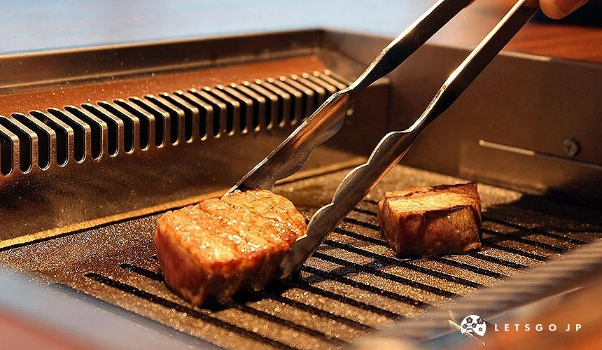 用夾子在烤一塊厚片的肉