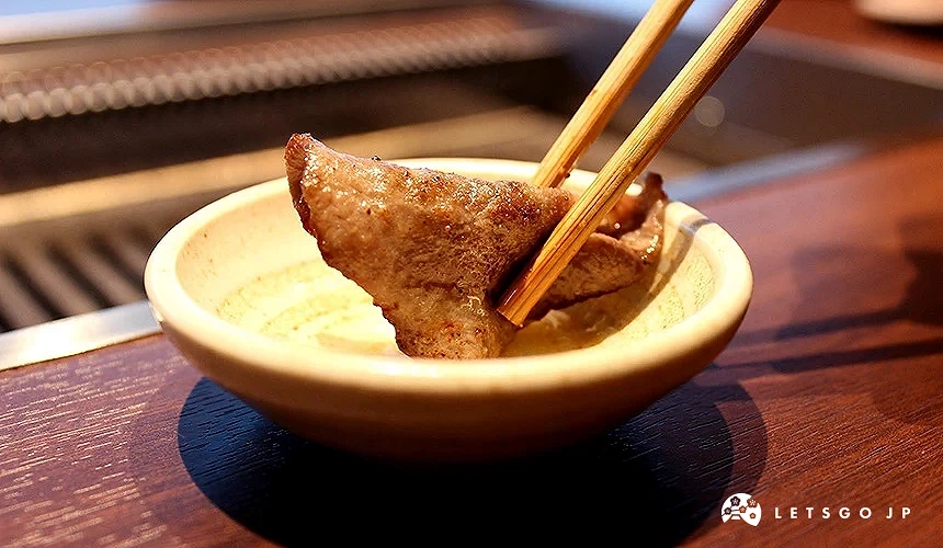 夾著烤過的牛舌沾醬汁