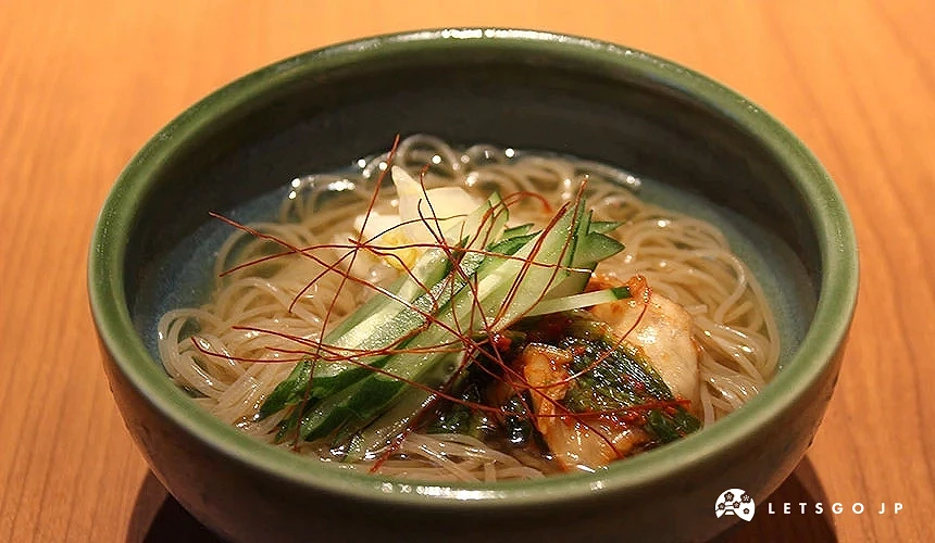 碗中放著冷麵、小黃瓜與泡菜