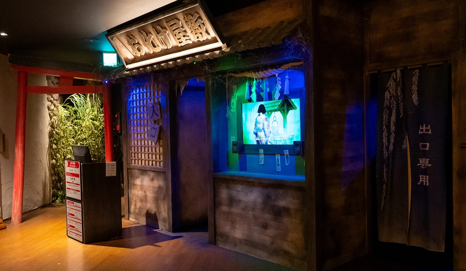 鬼屋門口旁播放著鬼屋主題的前導短片,入口處散發詭異綠燈